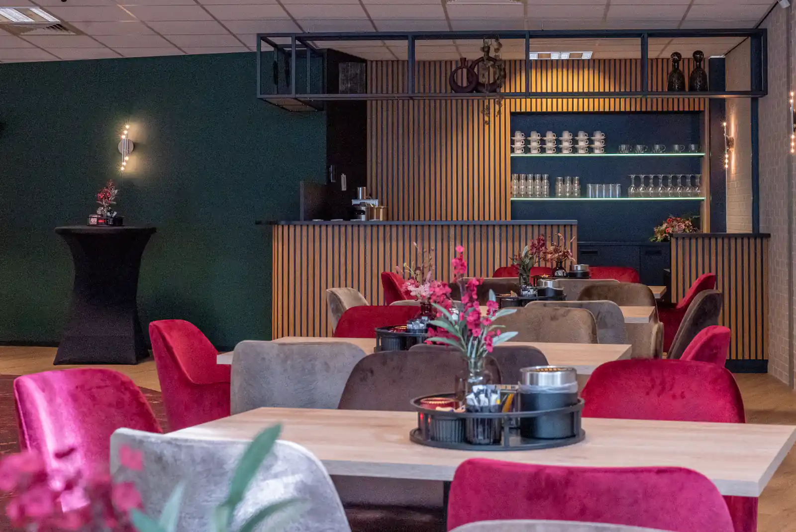 Ontmoetingsruimte met warme kleuren, tafels en een koffiebar